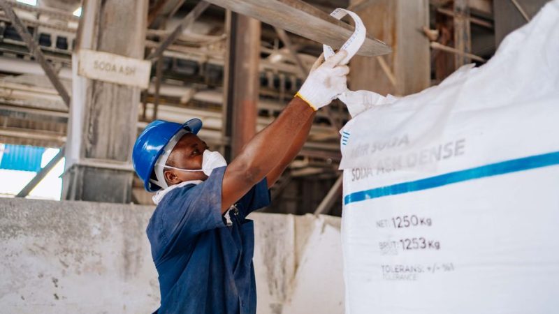 FIBC bulk bags manufacturer: industrial warehouse interior with rows of stacked FIBC bulk bags in natural daylight, concrete